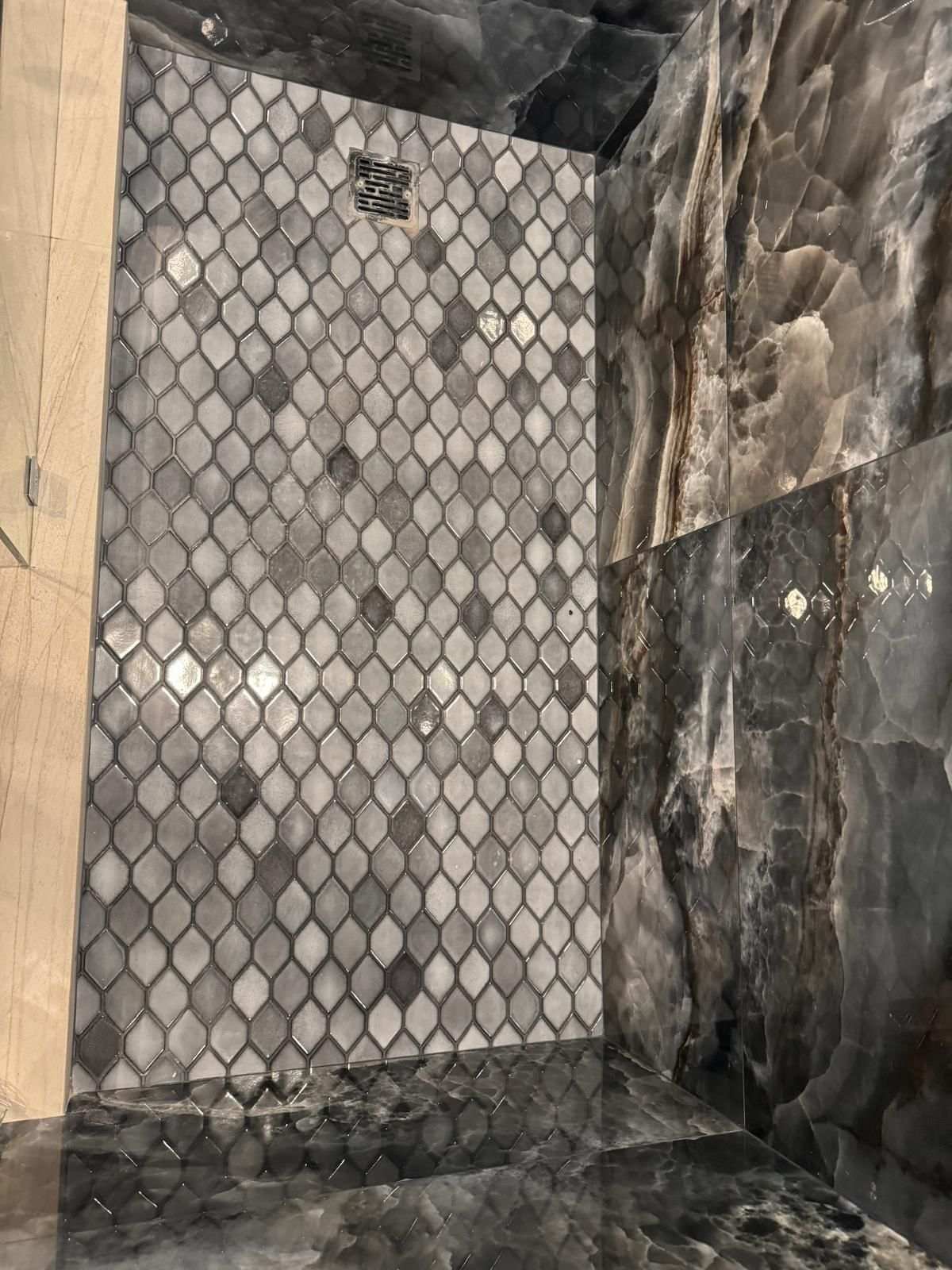 Arabesque mosaic shower wall against dark natural stone