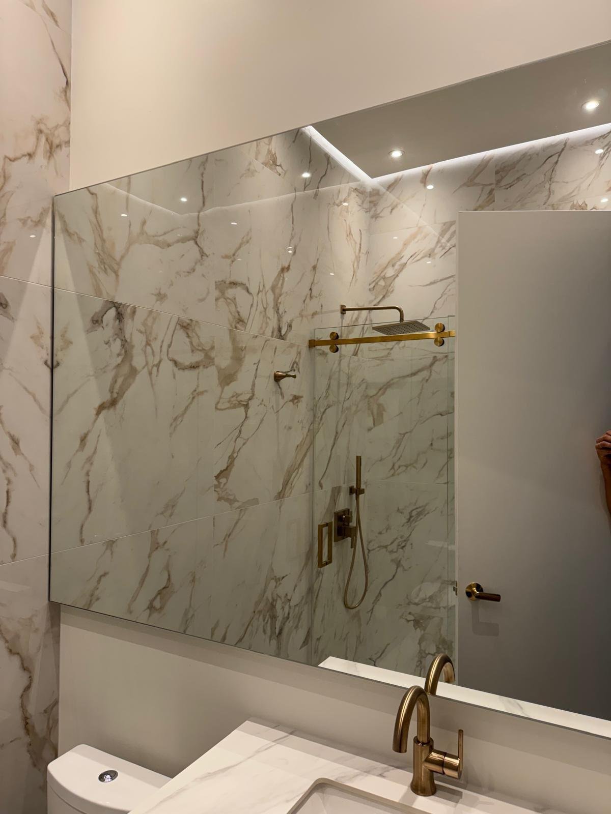 Calacatta marble bathroom wall with brushed brass fixtures and a full-width mirror