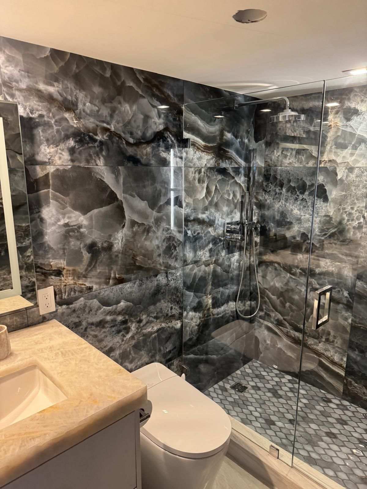 Dark marble bathroom with a walk-in shower and frameless glass panel