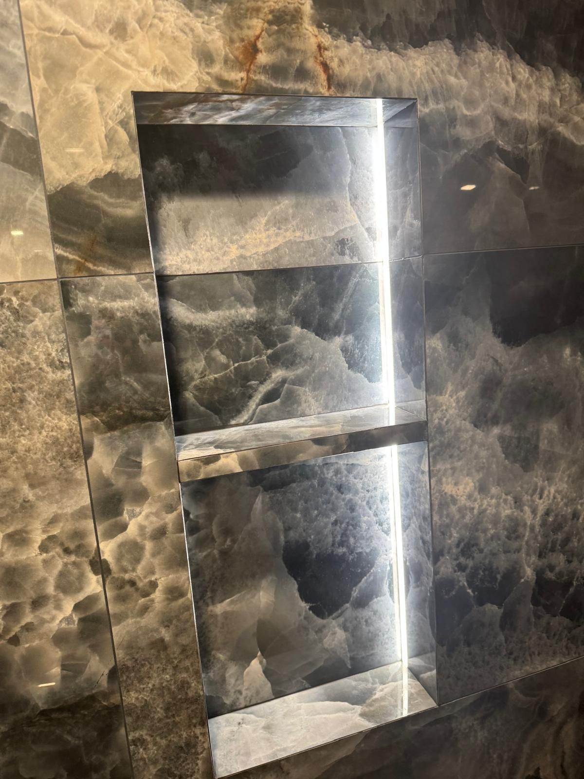 Dark natural stone shower wall with a vein-matched recessed niche