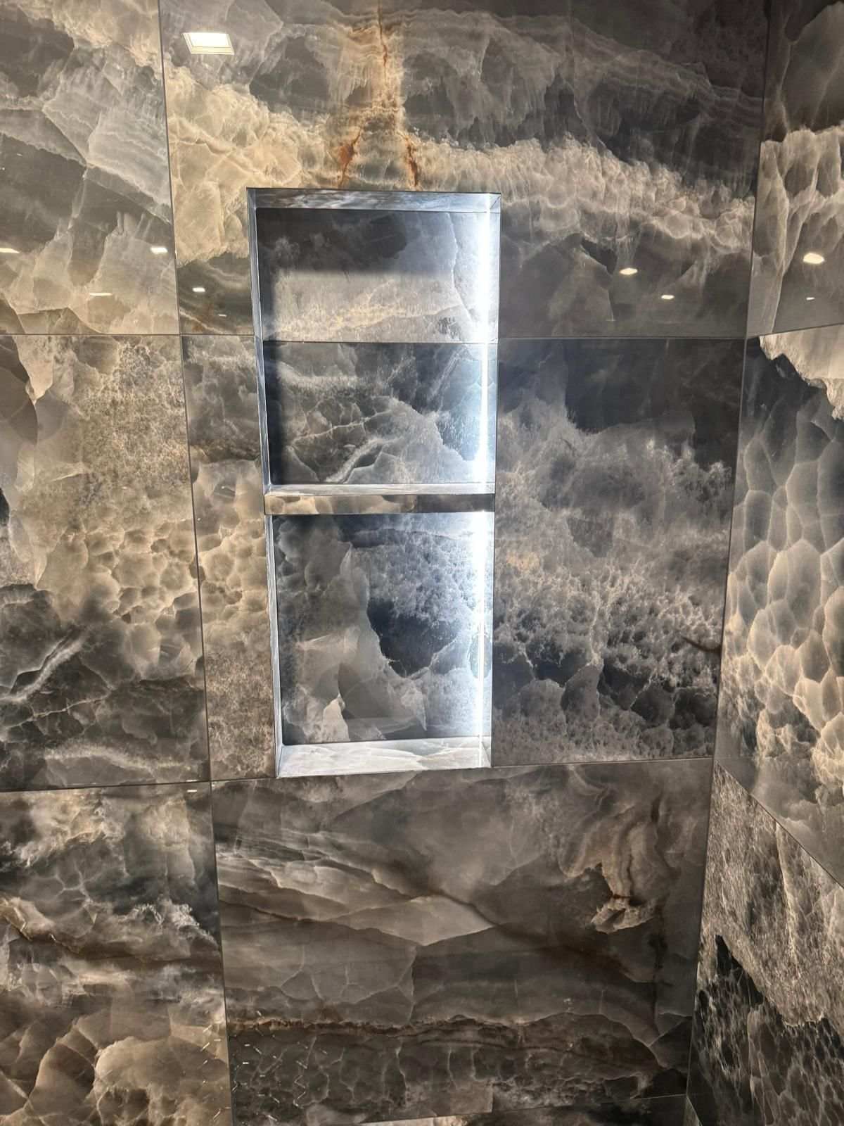 Dark stone shower wall with a full-height recessed niche
