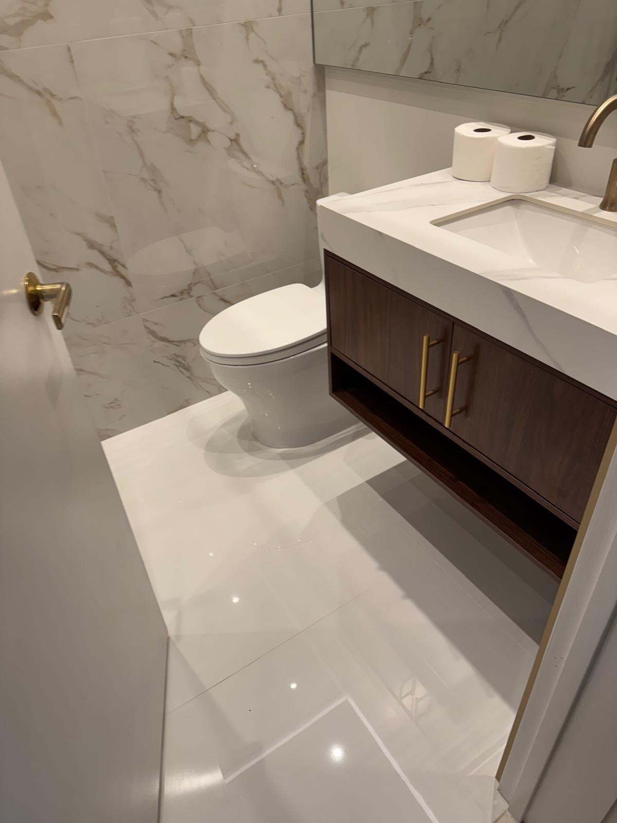 Floating walnut vanity against a marble wall in a finished bathroom