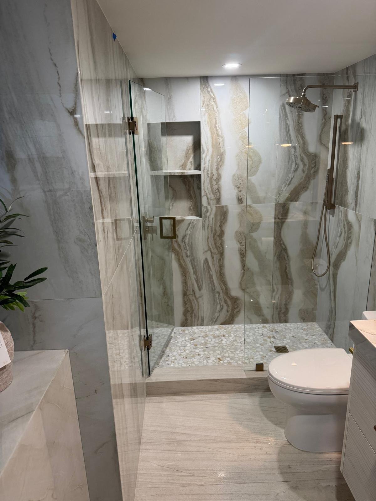 Frameless glass shower enclosure with natural stone walls and mosaic floor