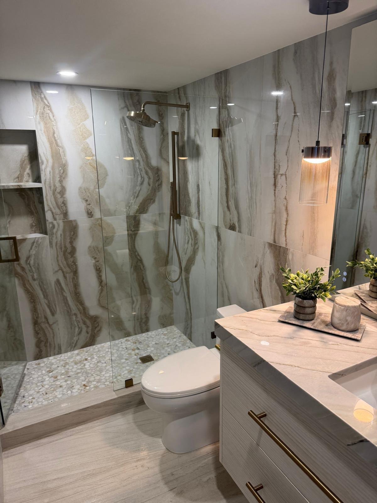 Luxury bathroom with book-matched natural stone shower walls and a floating vanity
