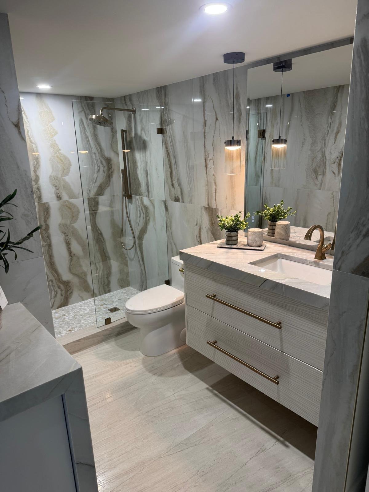 Completed luxury bathroom remodel with a walk-in glass shower and large-format porcelain walls