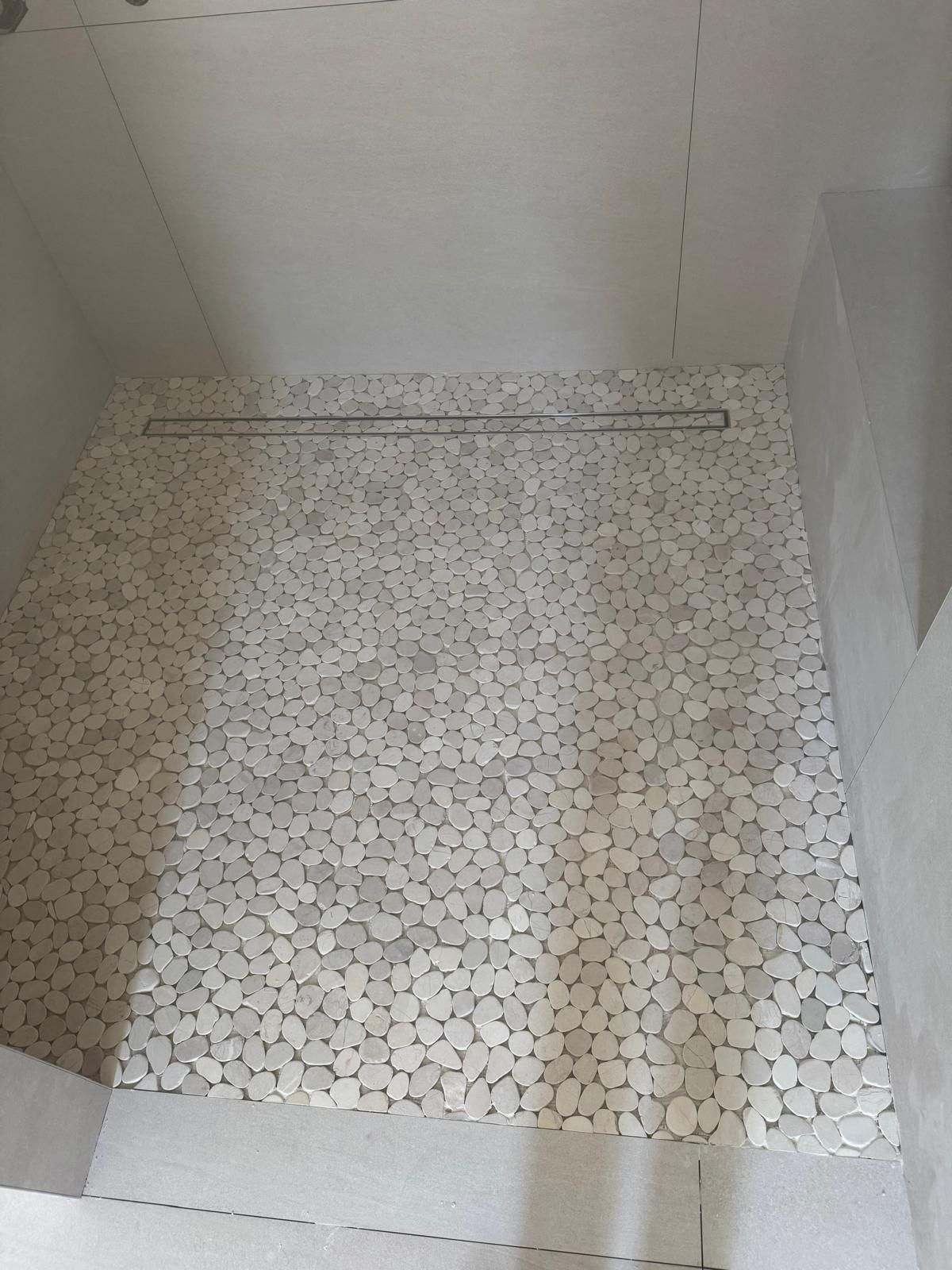 Pebble mosaic shower floor sloped to a linear drain